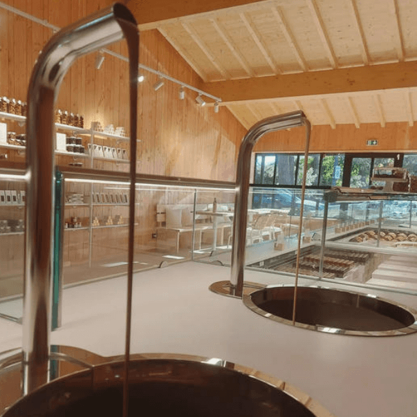 Fontaines à chocolat coulant dans des cuves inox intégrées au comptoir d'un bar à chocolat