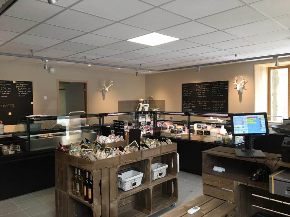 Vue d'ensemble de la boucherie-traiteur fromagerie avec vitrines réfrigérées noires et mobilier en caisses de bois