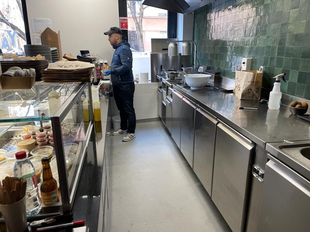Arrière-comptoir inox avec tables réfrigérées et plonge dans un restaurant de falafels