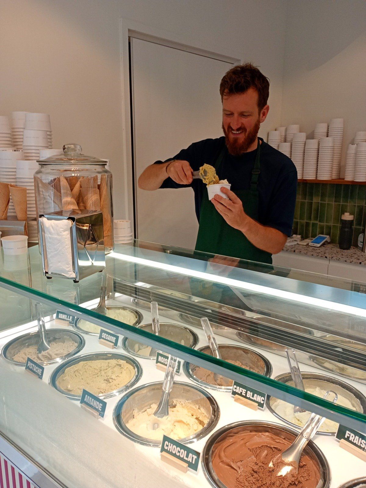 Artisan glacier servant une glace à la spatule depuis une vitrine à carapines