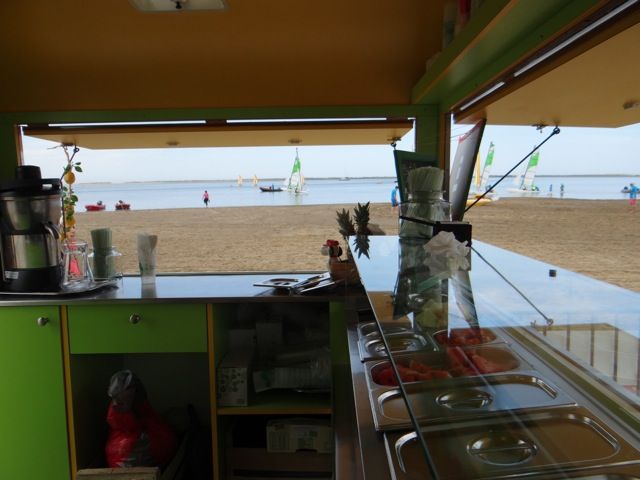 Bacs GN de garnitures réfrigérés sous vitrage dans une roulotte de snack face à la plage