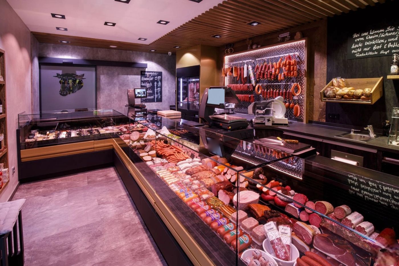 Boucherie-charcuterie traditionnelle avec comptoir réfrigéré en angle garni de charcuterie, jambons et saucisses, mur de saucissons