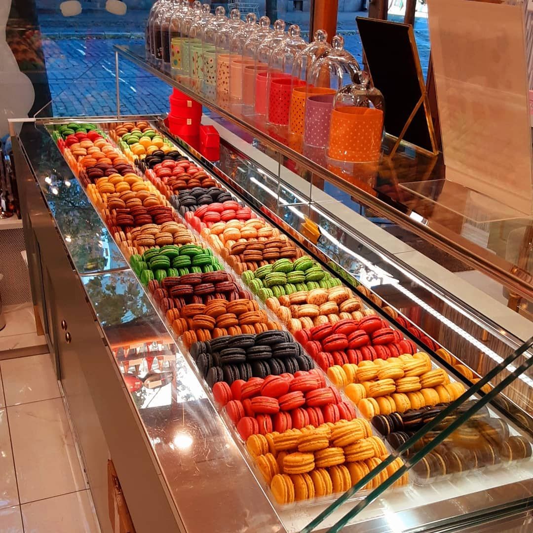 Longue vitrine basse garnie de rangées de macarons multicolores