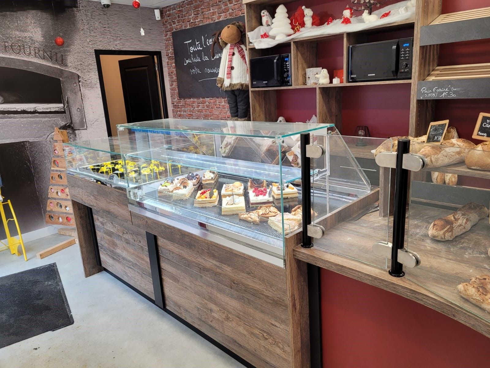 Comptoir de boulangerie en bois avec vitrine réfrigérée de pâtisseries et présentation des pains