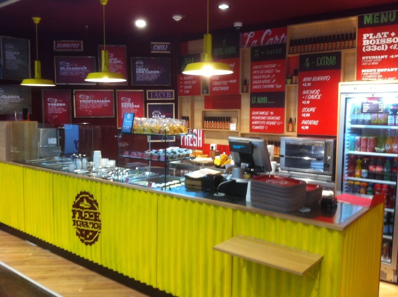 Comptoir de restaurant tex-mex avec façade en tôle ondulée jaune et bacs de garnitures
