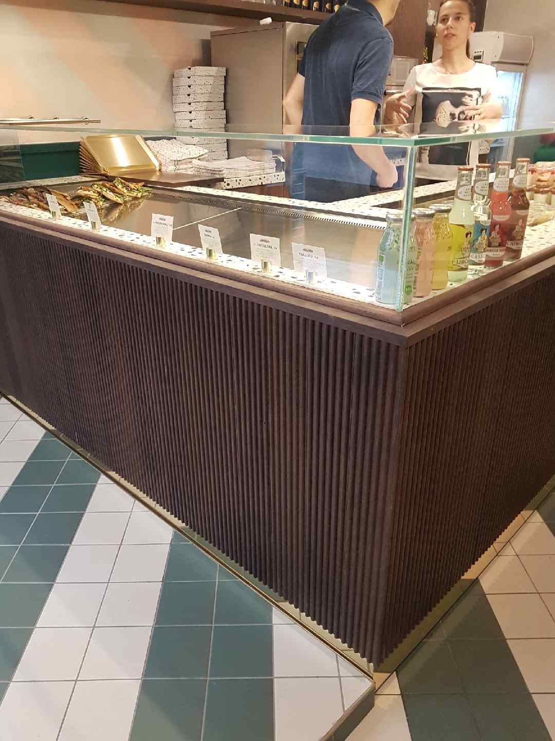Comptoir d’angle de pizza al taglio avec façade en bois cannelé et vitrage droit