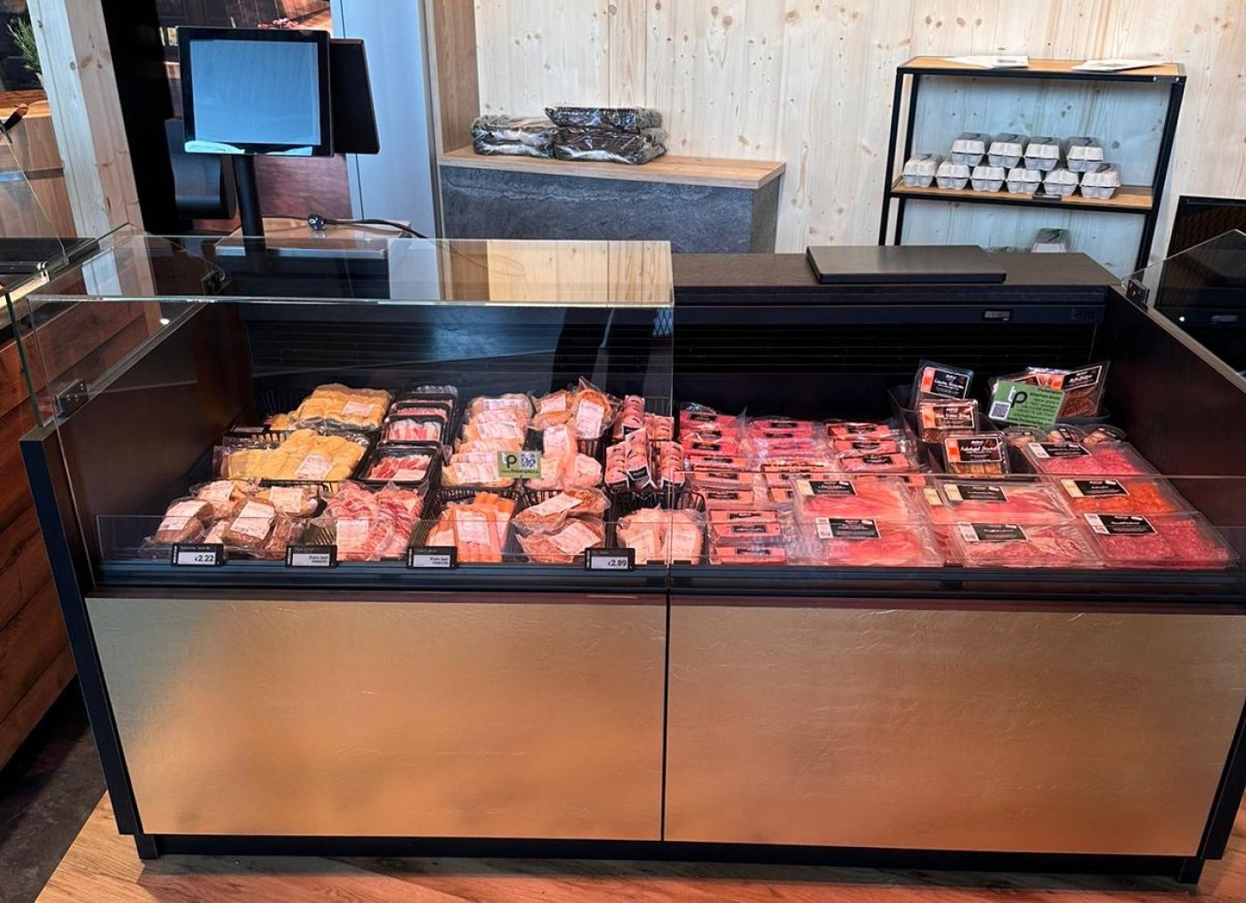 Comptoir réfrigéré compact de boucherie-charcuterie avec façade dorée, garni de charcuterie et viandes conditionnées