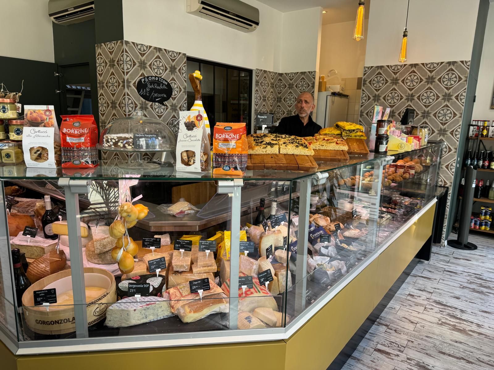 Comptoir réfrigéré de trattoria garni de fromages italiens, de charcuteries et de focaccias