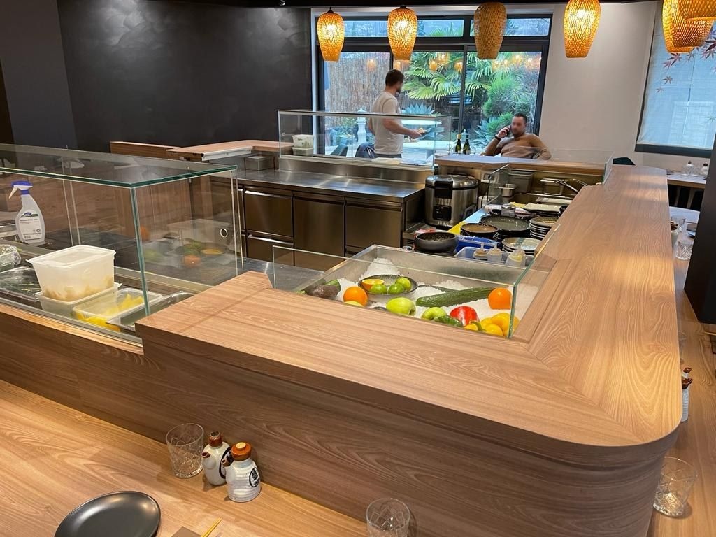 Comptoir de sushi bar avec vitrine réfrigérée à poissons et légumes, poste de préparation