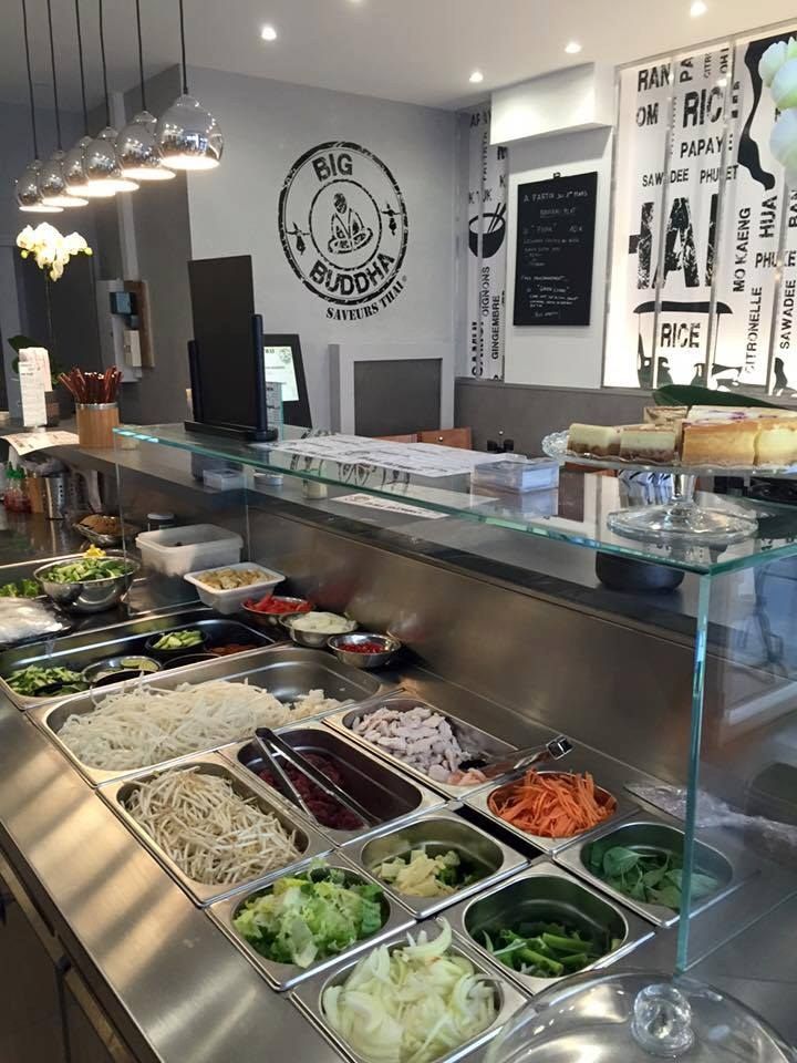 Comptoir de restaurant de wok avec bacs d’ingrédients réfrigérés sous vitrage : nouilles, légumes et viandes