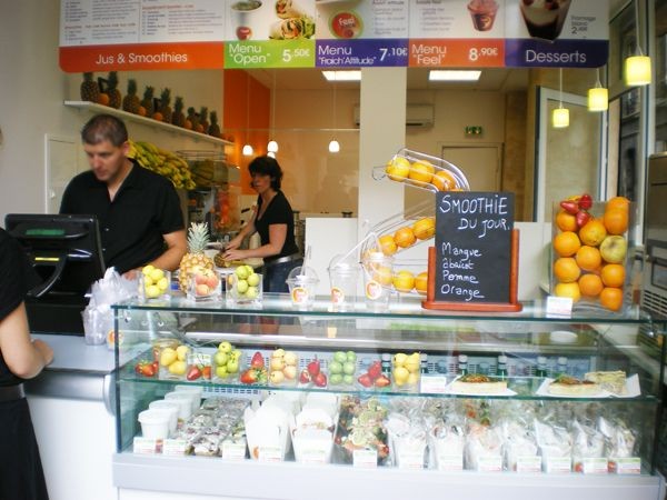 Bar à jus : comptoir vitrine à fruits frais et smoothies, équipe en service