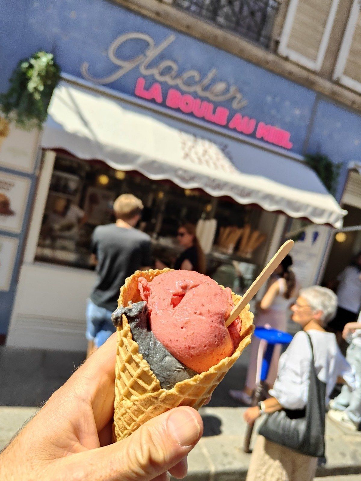 Cornet de glace artisanale à emporter devant la façade d’un glacier parisien