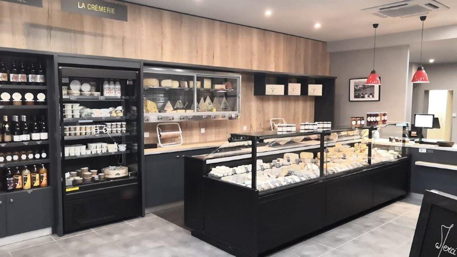 Crémerie-fromagerie équipée d’un comptoir réfrigéré noir et de murales froides pour fromages et produits laitiers