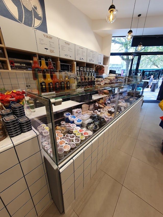 Comptoir réfrigéré habillé de carrelage blanc dans une épicerie fine parisienne