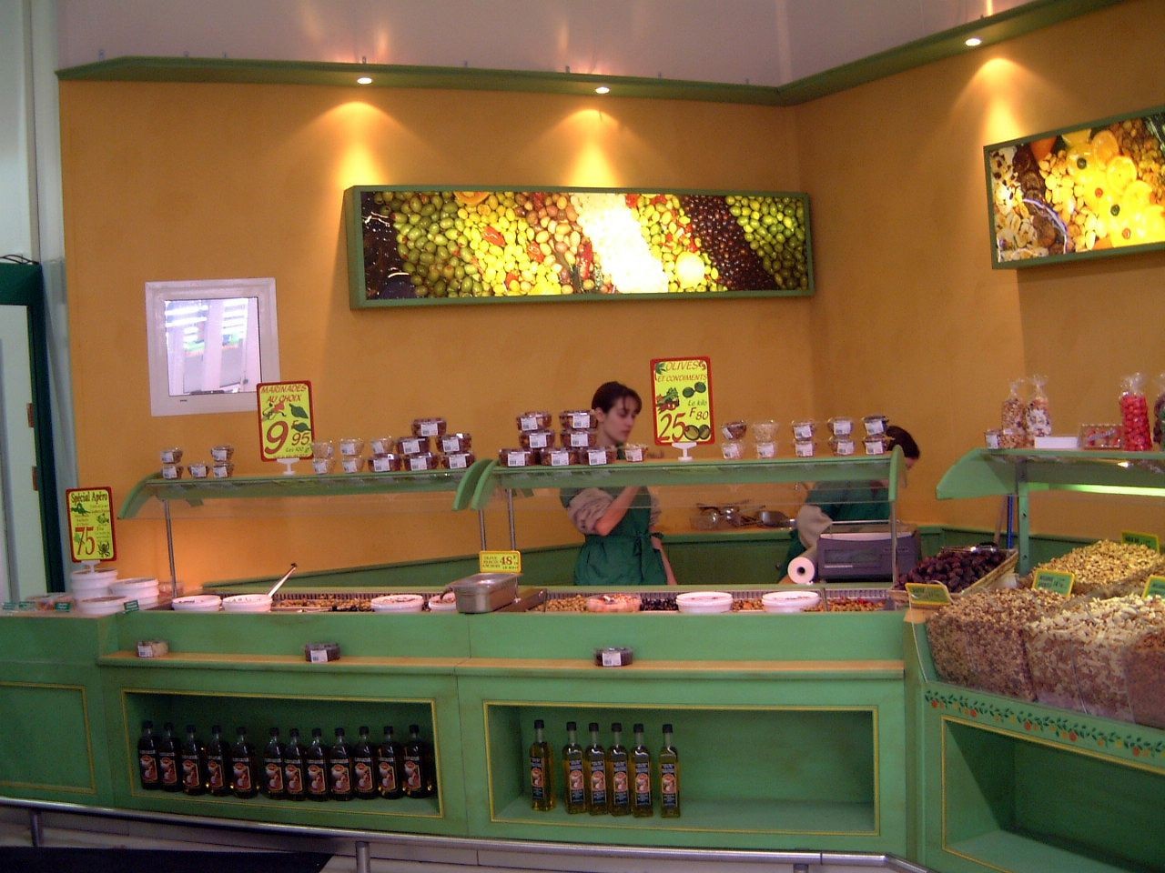 Comptoir à olives, épices et fruits secs avec vendeuse, panneaux lumineux décoratifs au mur