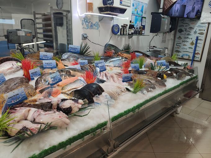 Agencement de poissonnerie : étal à glace de poissonnerie garni de poissons entiers, de filets et de saumon