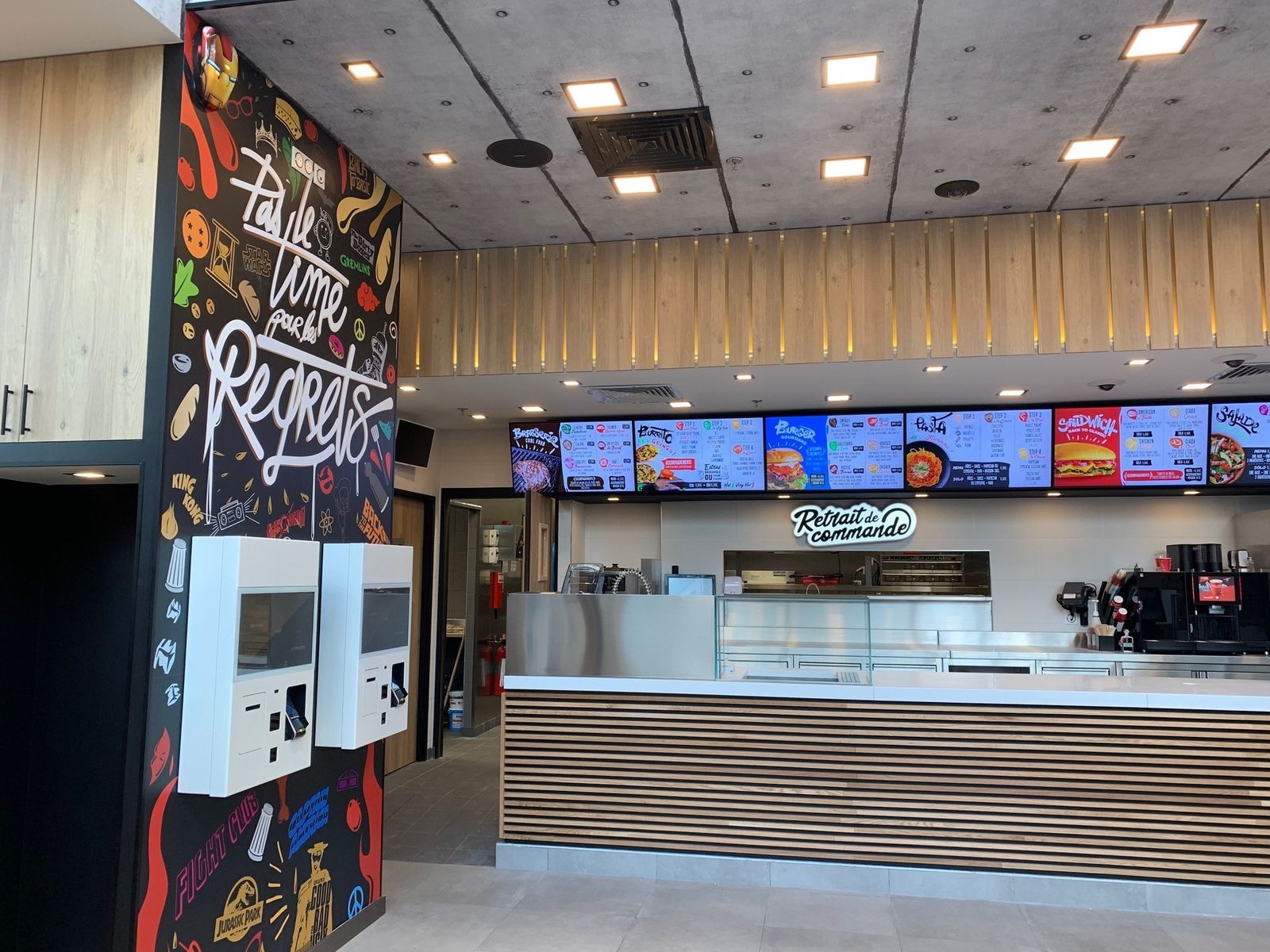 Agencement de fast-food : restaurant rapide avec bornes de commande, écrans menus et comptoir de retrait à lames bois
