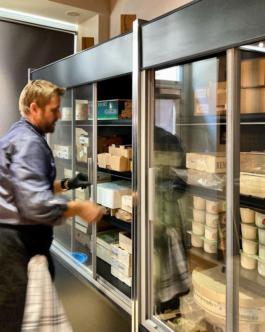 Fromager ouvrant une murale réfrigérée à portes vitrées coulissantes garnie de fromages