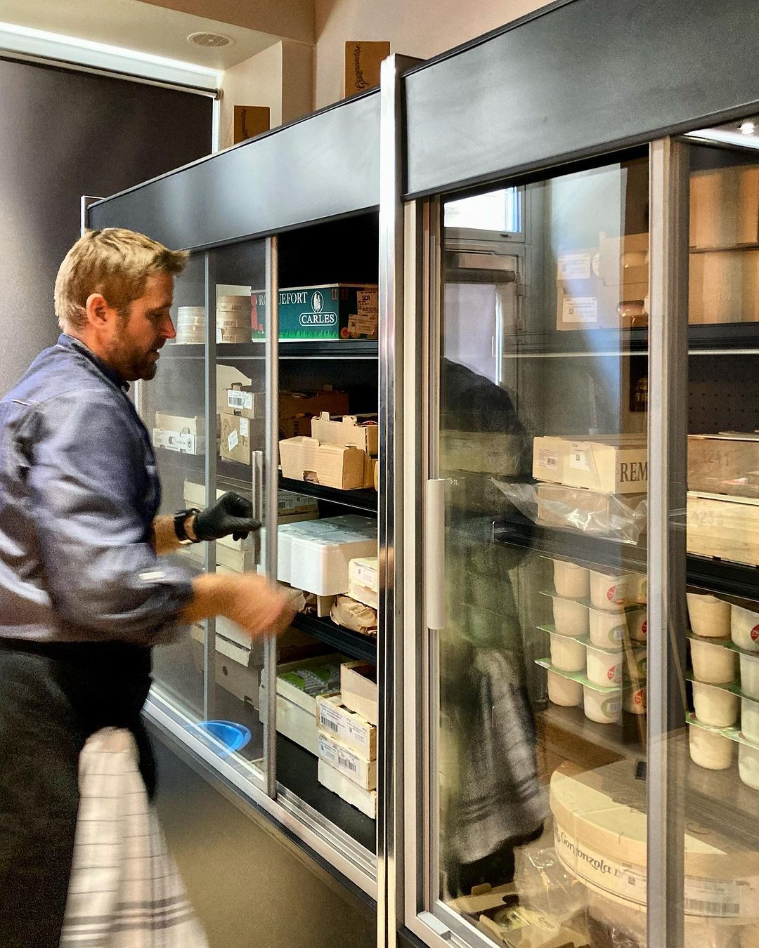 Fromager ouvrant une murale réfrigérée à portes vitrées coulissantes garnie de fromages