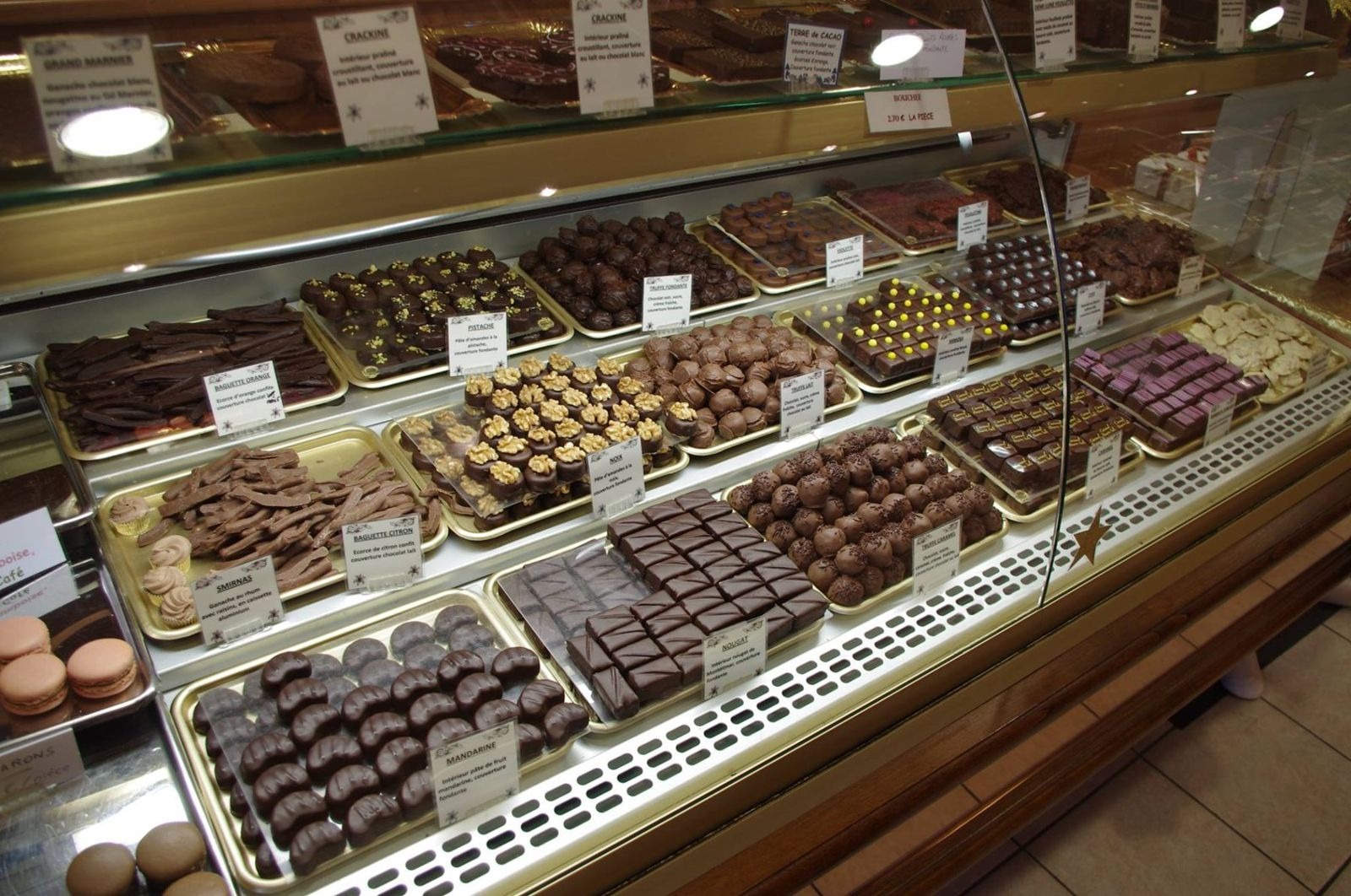 Vitrine réfrigérée à chocolats avec pralinés et ganaches présentés sur plateaux