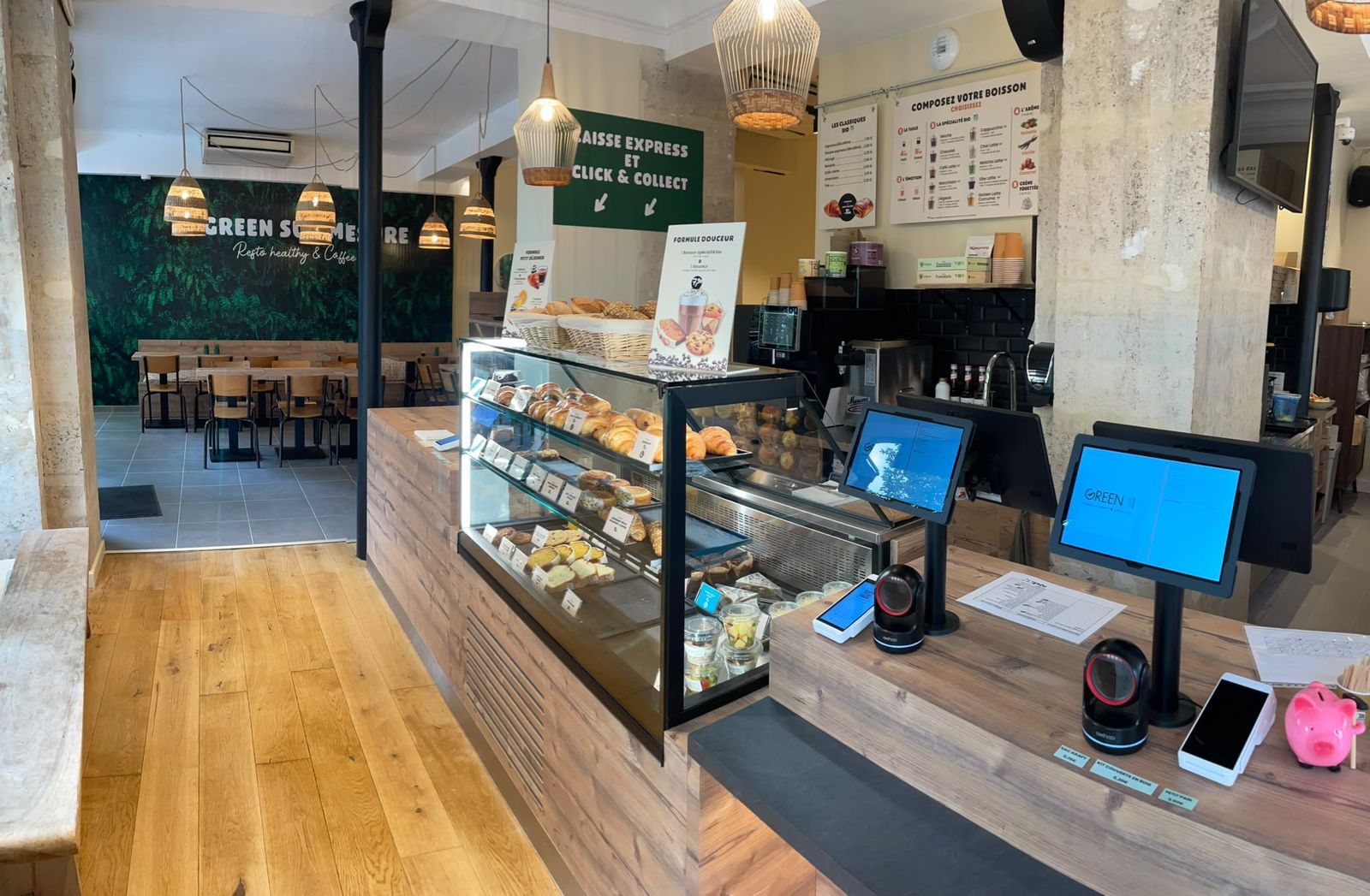 Comptoir en bois d’un restaurant healthy de franchise avec vitrine réfrigérée et bornes de caisse, Paris