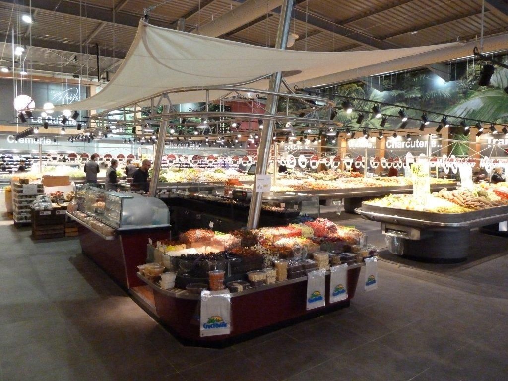 Kiosque à olives et fruits secs sous voile d’ombrage dans une grande halle alimentaire