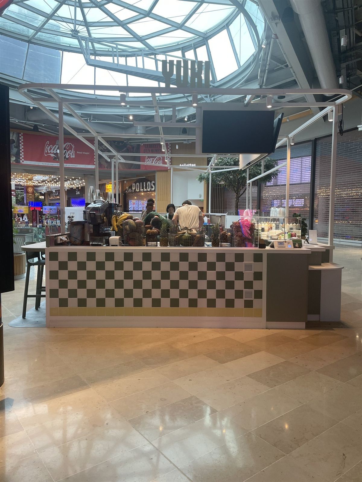 Vue d’ensemble d’un kiosque de poké bowl dans un food court sous verrière