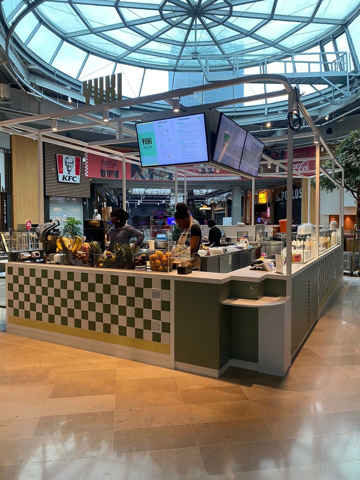 Kiosque sur mesure à structure métallique blanche et écrans sous une verrière de centre commercial