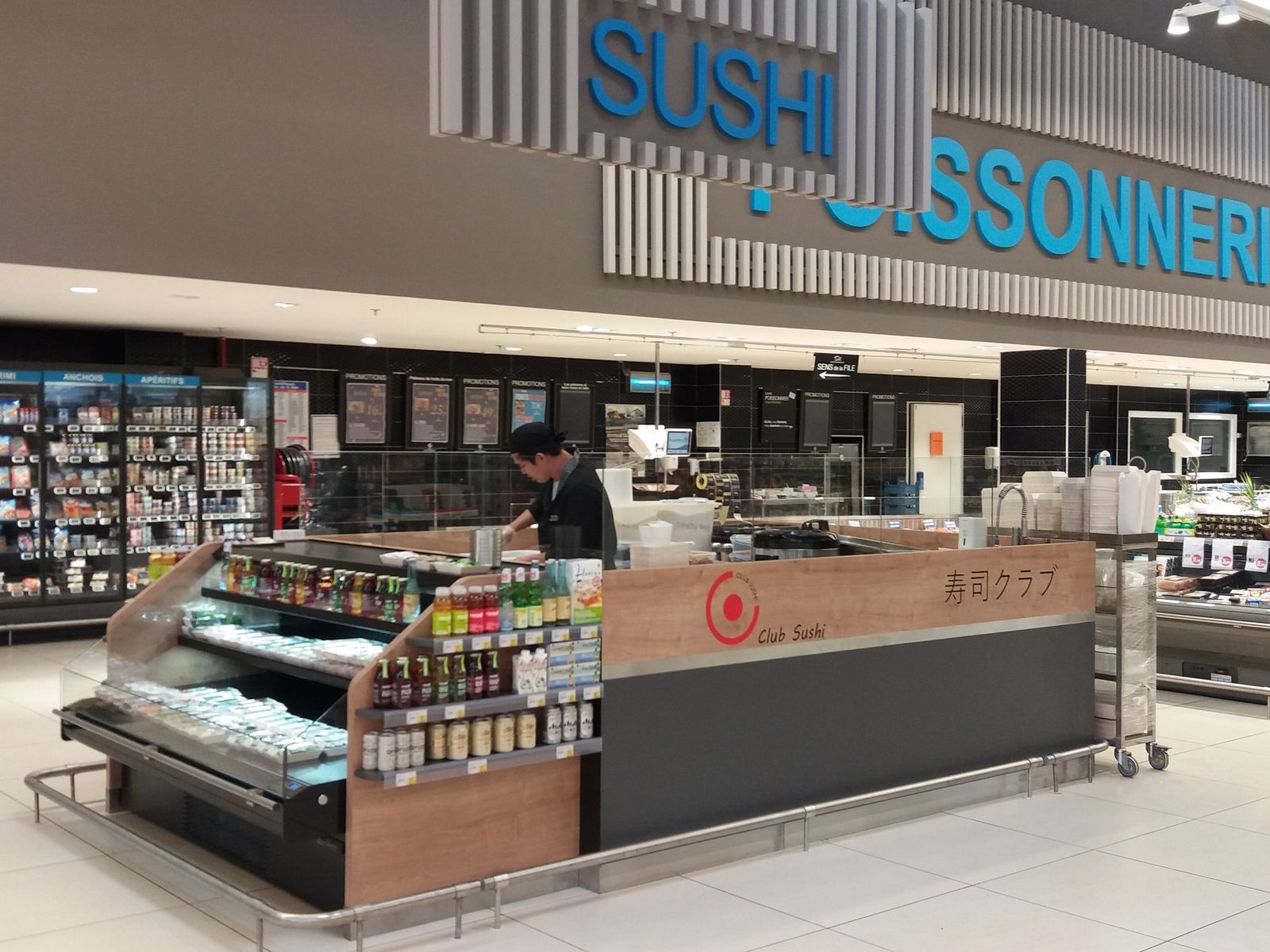 Kiosque à sushis sur mesure en hypermarché avec vitrine réfrigérée libre-service, façade bois et préparation à la vue des clients