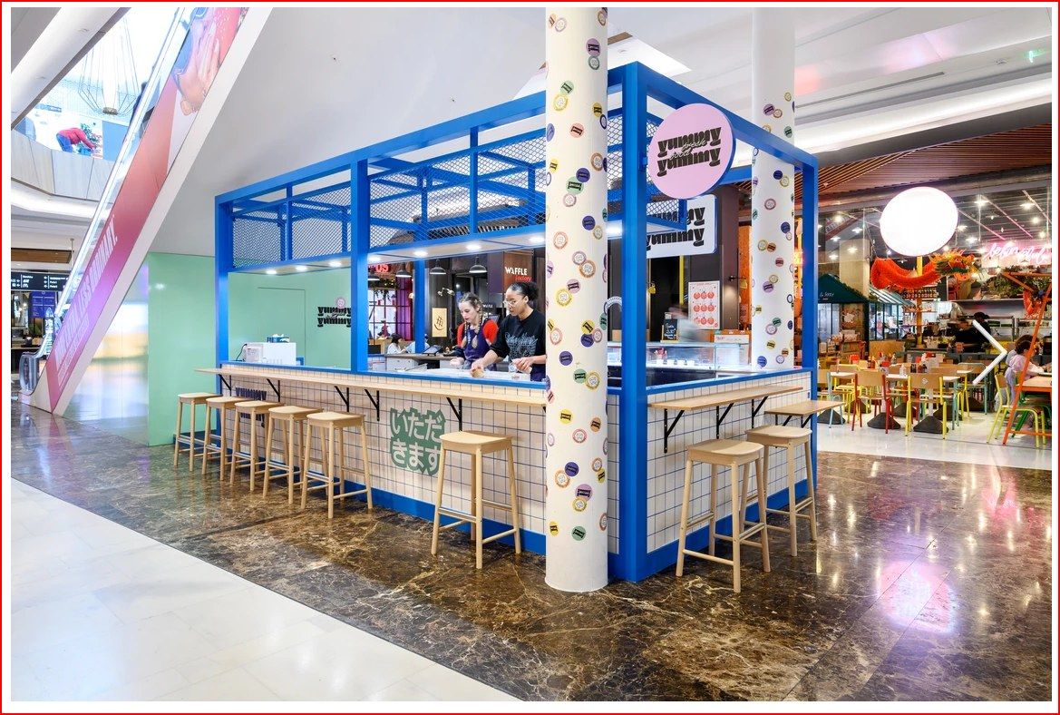 Kiosque Yummy Yummy en centre commercial avec structure bleue, comptoir carrelé et tabourets
