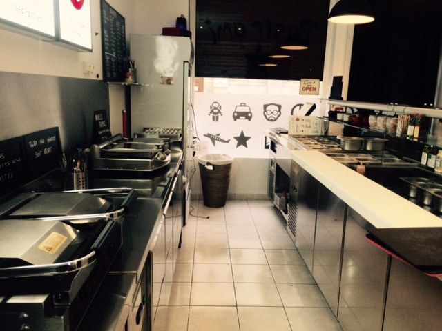 Ligne chaude de snack avec grill, plancha et plan inox face au comptoir de service