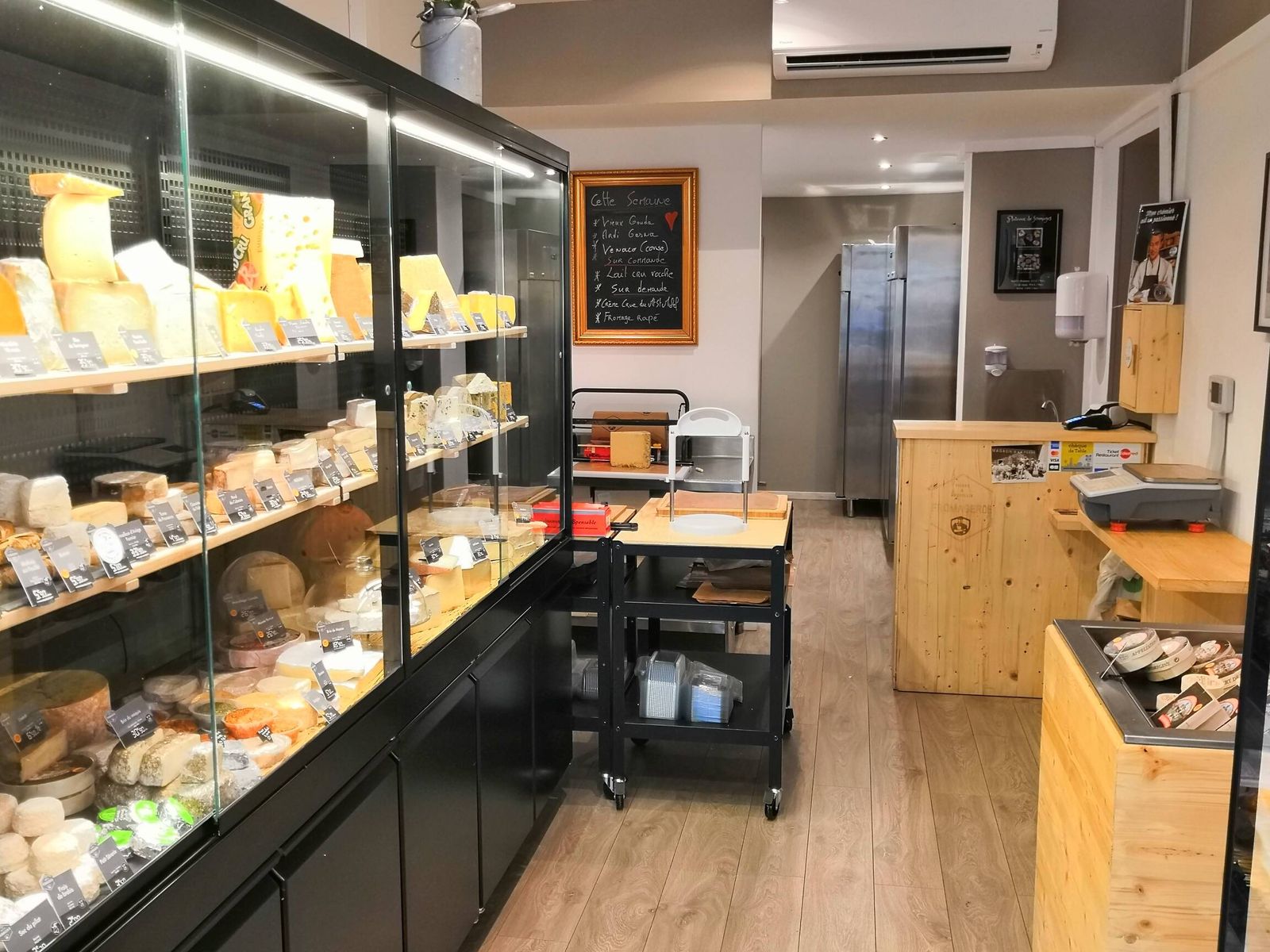 Murale réfrigérée sur mesure à façade noire et étagères garnies de fromages dans une fromagerie lyonnaise