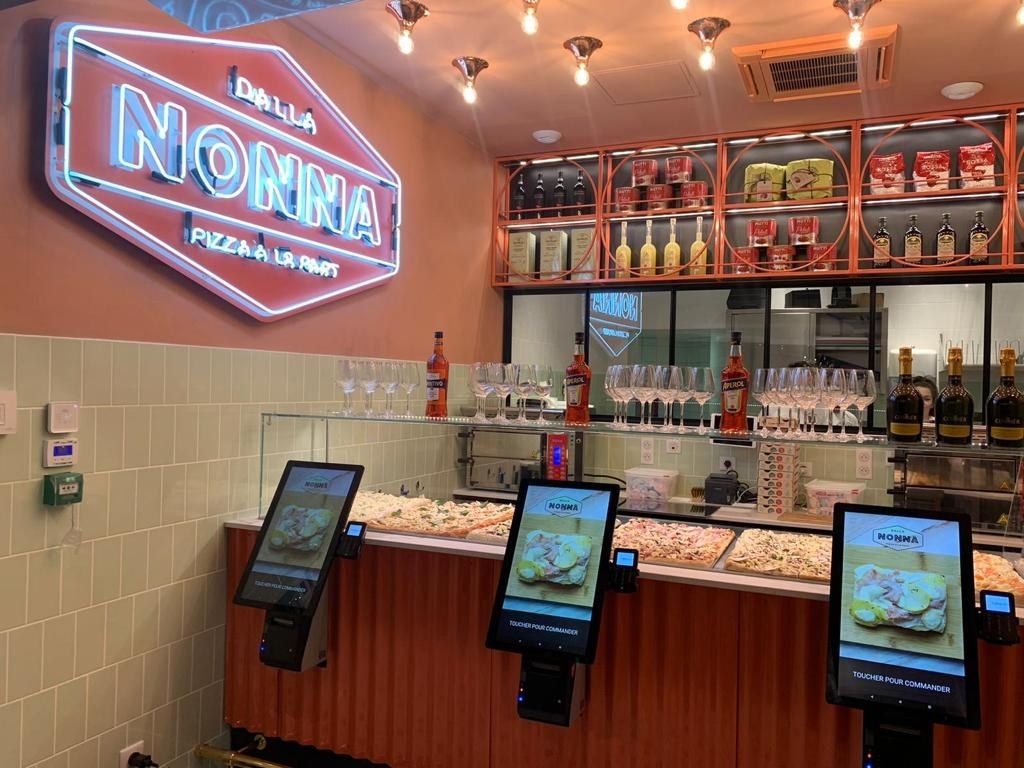 Pizzeria à la part Dalla Nonna : comptoir de plaques sous vitrage et bornes de commande
