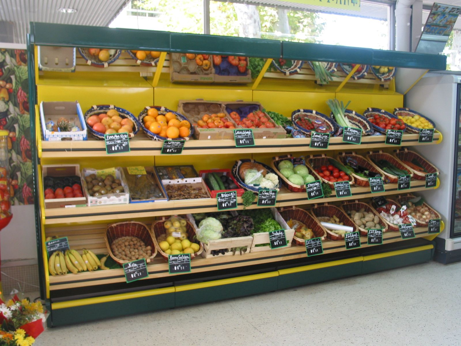 Rayon fruits et légumes en paniers et cagettes inclinés dans une supérette