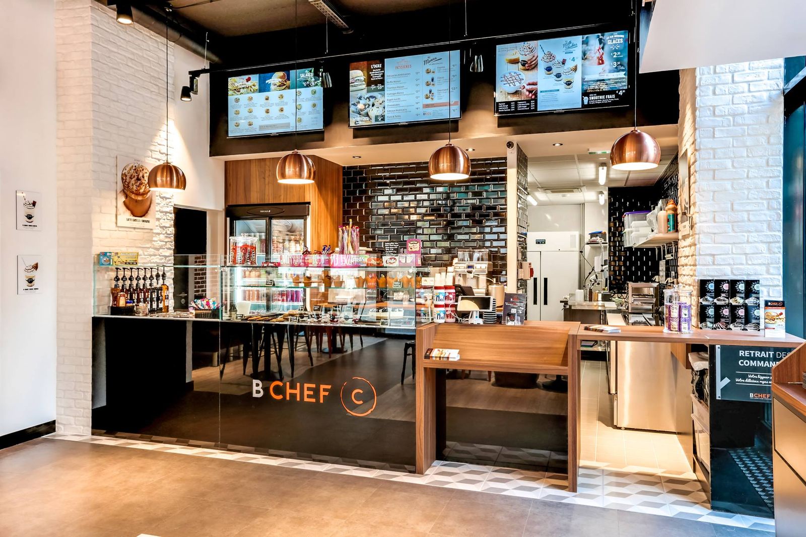 Restaurant de bagels et burgers : comptoir noir, suspensions cuivre et écrans de menus