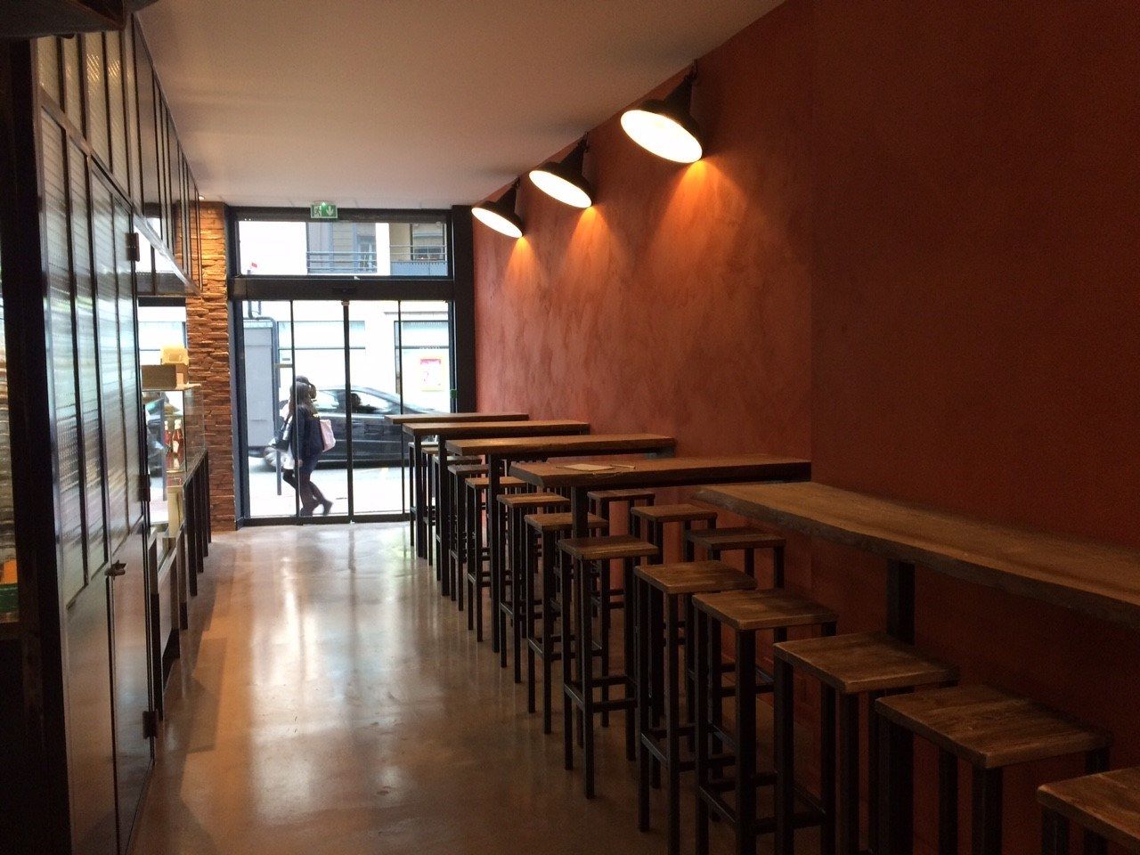 Salle d’un restaurant de falafels avec mange-debout en bois et éclairage chaleureux