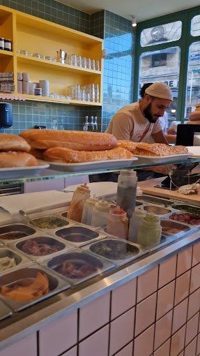 Poste de préparation de sandwicherie avec pains, sauces et bacs de garnitures réfrigérés