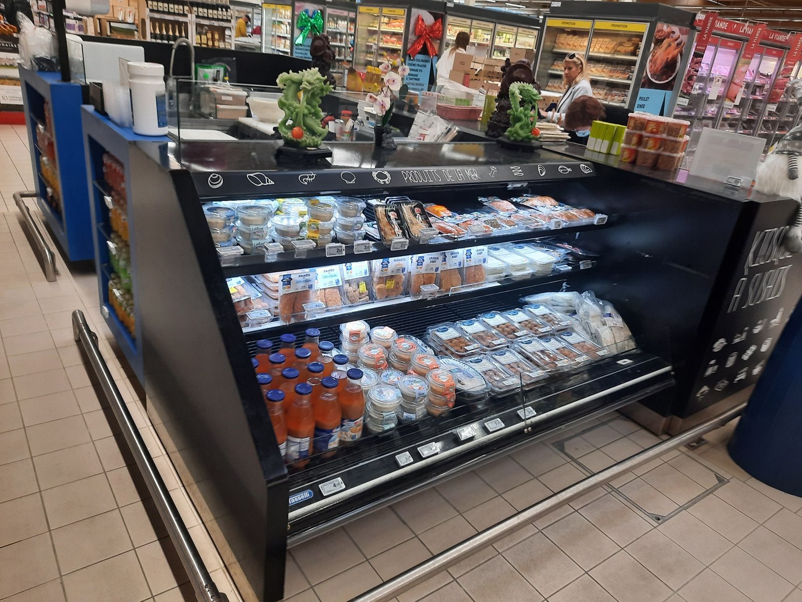Stand à sushis de supermarché avec vitrine réfrigérée inclinée et étagères de produits japonais