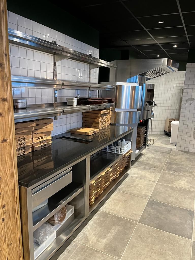 Table d’enfournement en inox avec étagères et rangement des boîtes à pizza devant la zone de cuisson