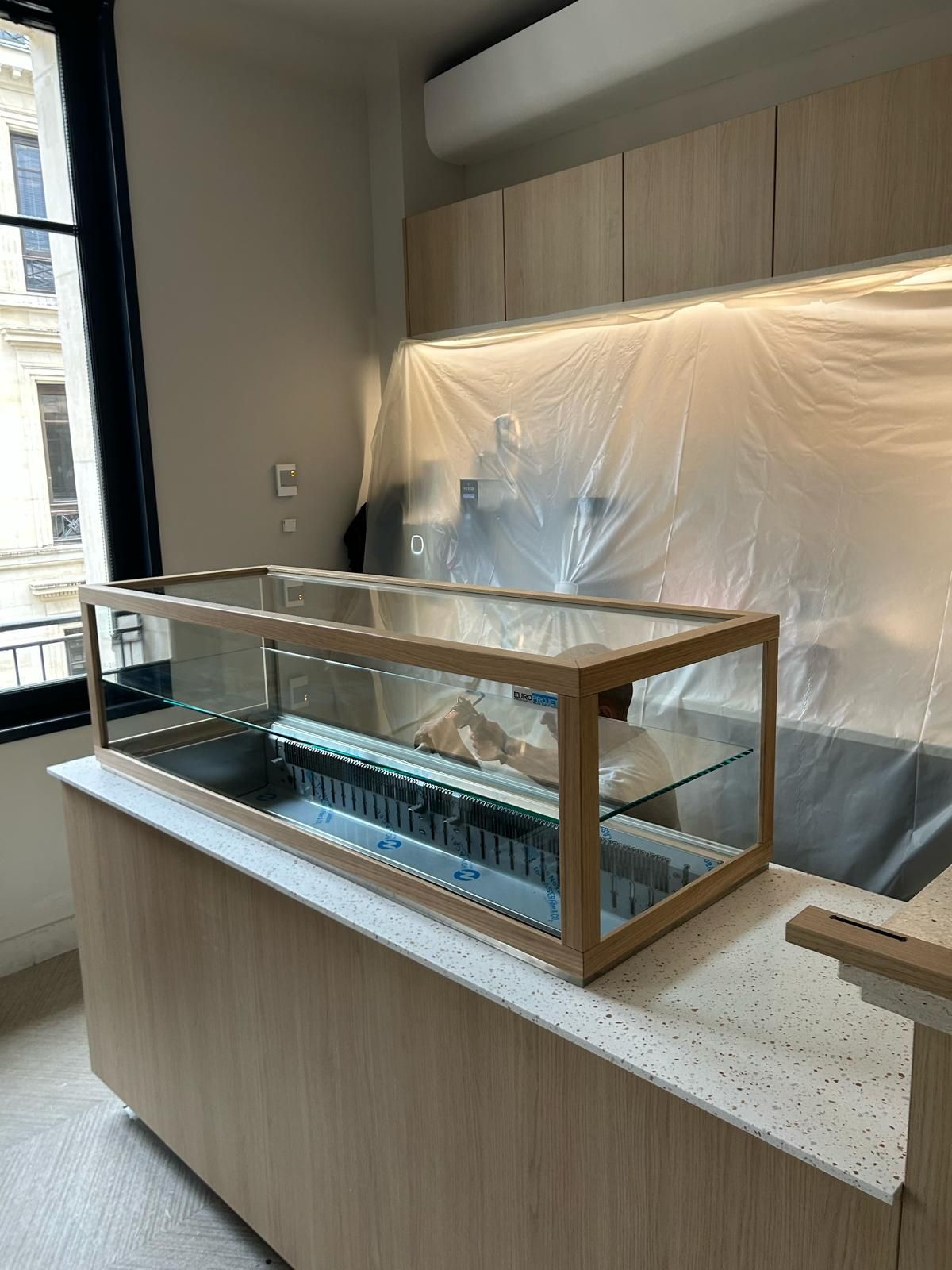 Vitrine à poser sur mesure à cadre bois et vitrage collé sur comptoir en terrazzo