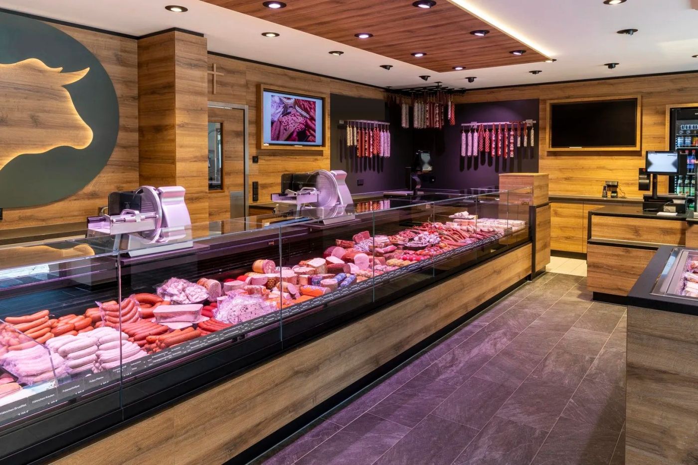 Boucherie-charcuterie au décor bois équipée d'un long comptoir réfrigéré double froid à vitrage droit