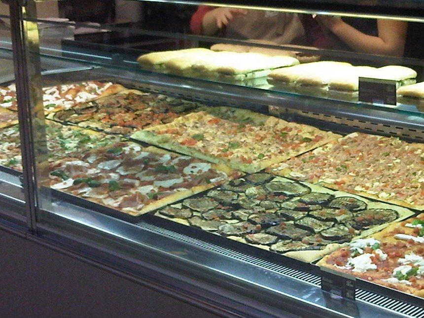 Vitrine de pizza à la part présentant des plaques de pizza et des focaccias