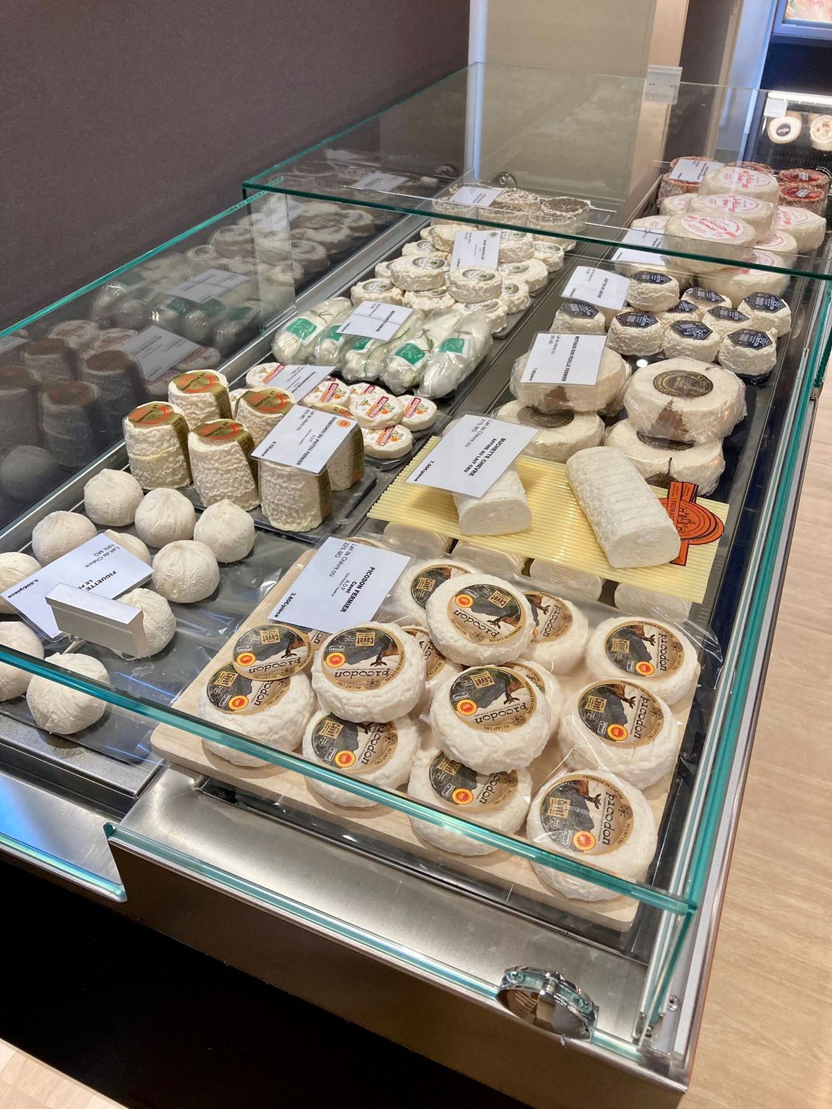 Vitrine réfrigérée plate à vitrage droit garnie de fromages de chèvre et de pâtes molles