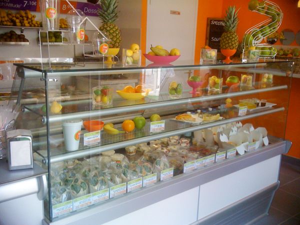 Vitrine réfrigérée de bar à jus avec fruits frais, salades et wraps