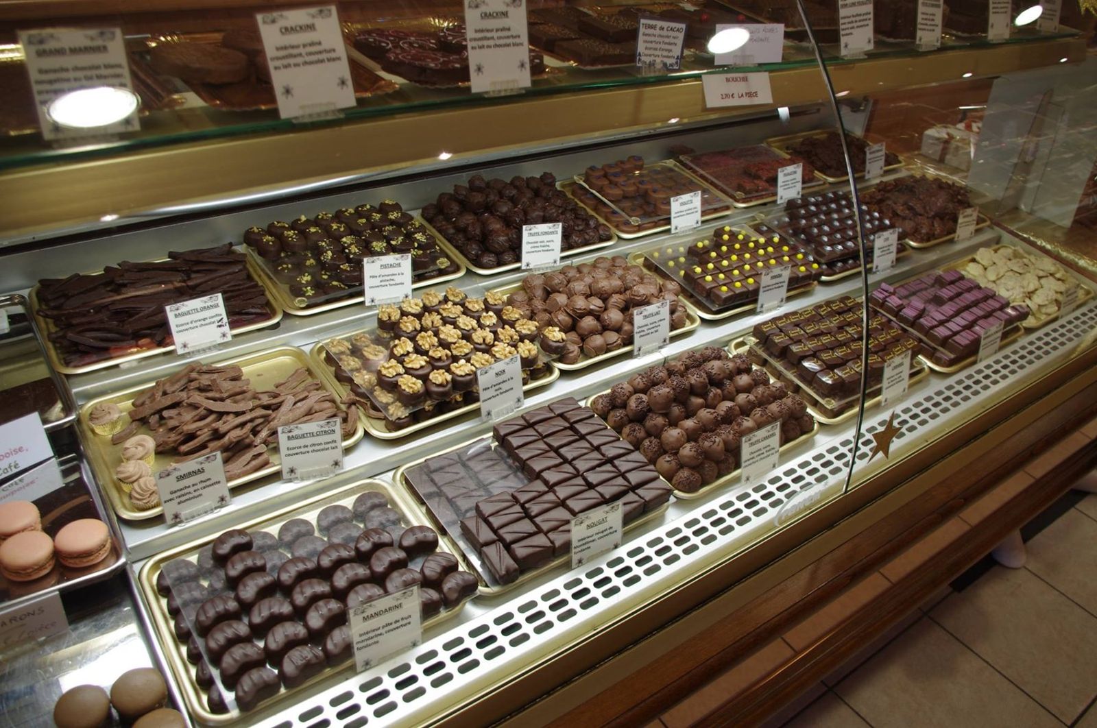 Vitrine réfrigérée à chocolats avec pralinés et ganaches présentés sur plateaux