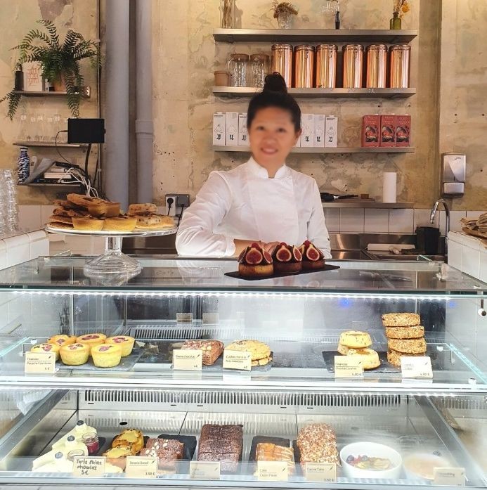 Cheffe pâtissière derrière une vitrine réfrigérée à pâtisseries dans un salon de thé