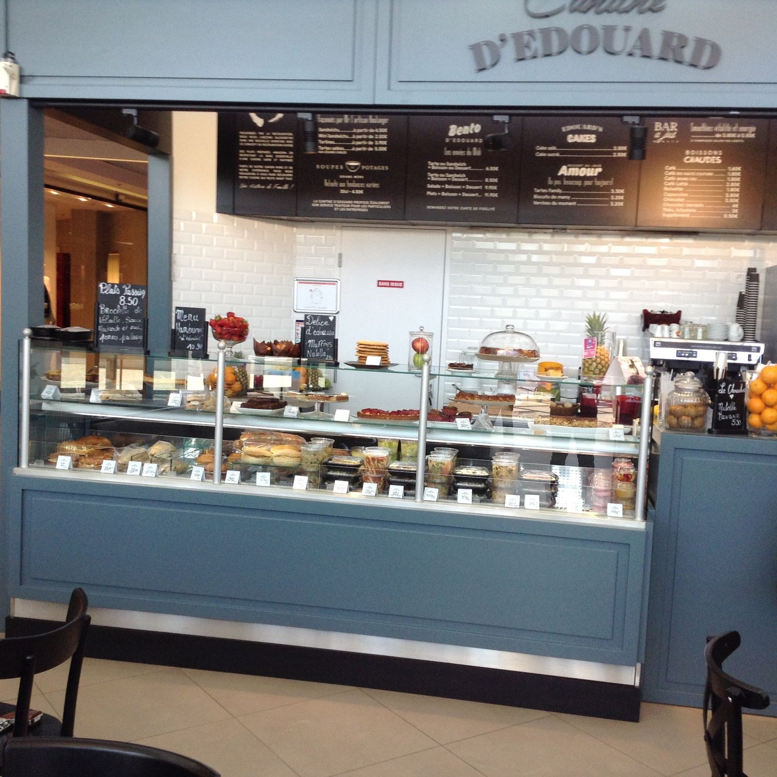 Vitrine réfrigérée de sandwicherie présentant sandwichs, salades et desserts sur un comptoir bleu