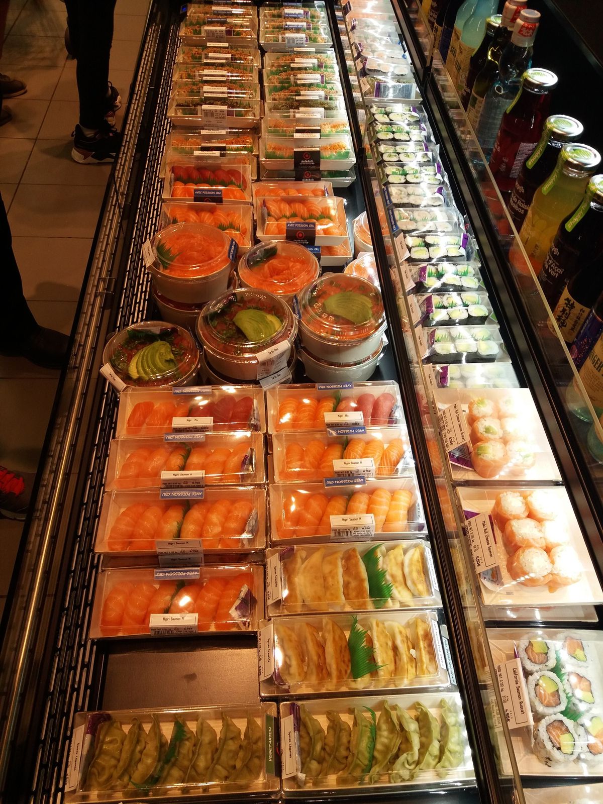 Vitrine réfrigérée de stand à sushis remplie de barquettes de makis et sashimis